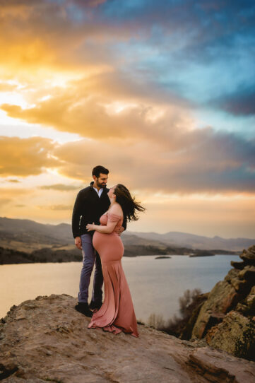 Maternity photo of a couple standing on a rock above Horsetooth Reservoir taken by Becky Michaud, Fort Collins Photographer