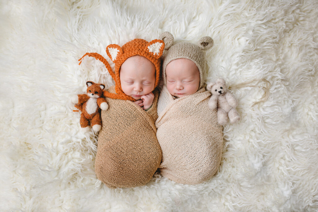 Newborn twins with fox and bear bonnets