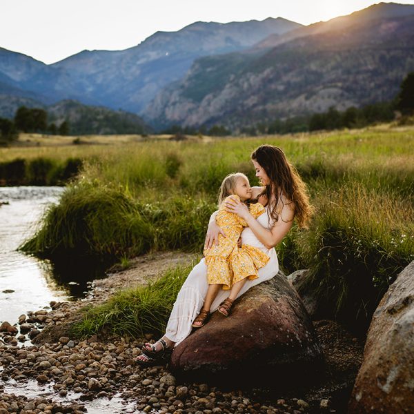 A mother snuggles her daughter as they pose for a photo in Rocky Mountain National Park